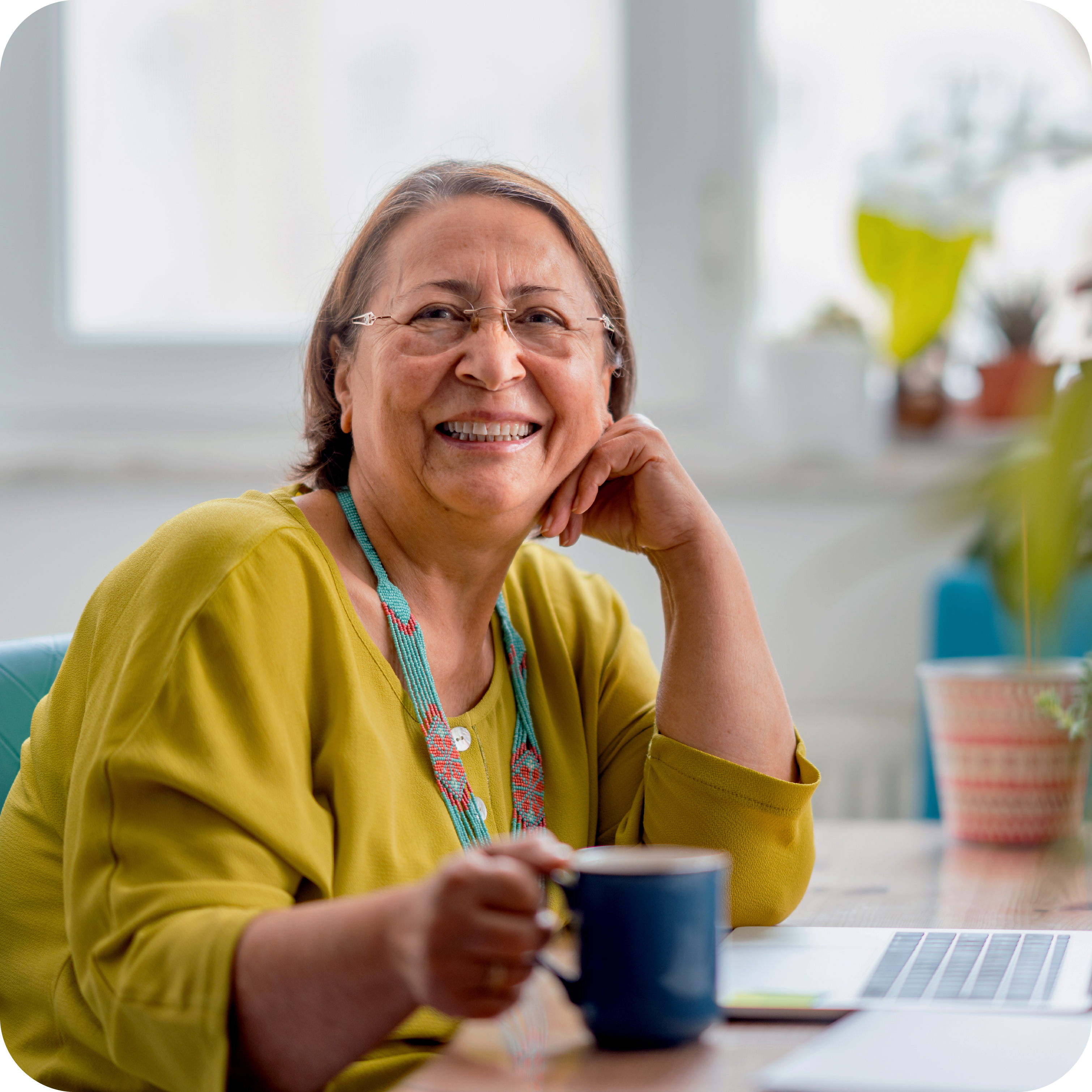 Woman smiling and sitting in front of a laptop on a desk.