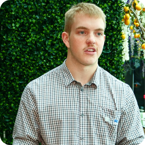Man standing in front of grass wall in plaid shirt 